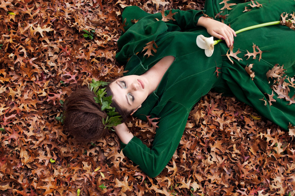 Sleeping Beauty wearing a green dress asleep in autumn leaves waits for the grand opening of Fab-you-liss Photography